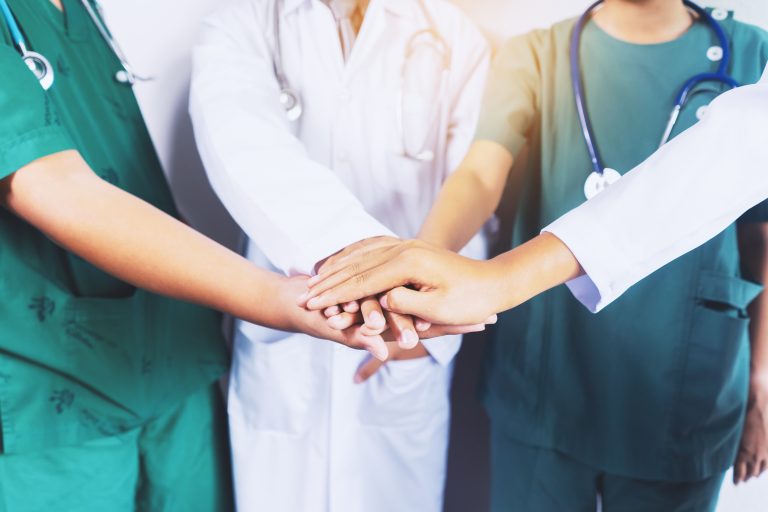 Healthcare professionals with their hands stack on top of one another