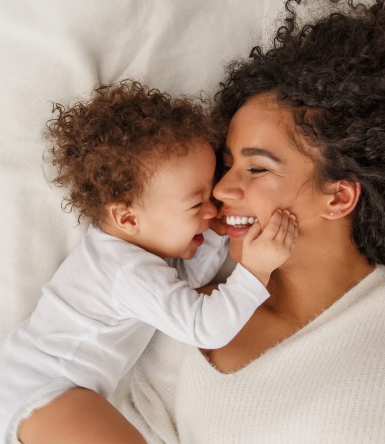 A mom and baby in bed laughing