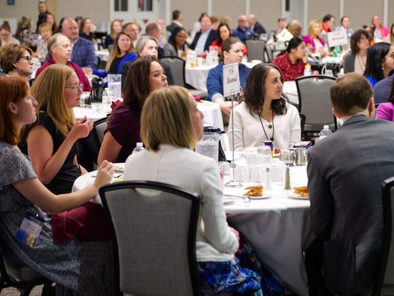 A group of people sitting at tables at a conference
