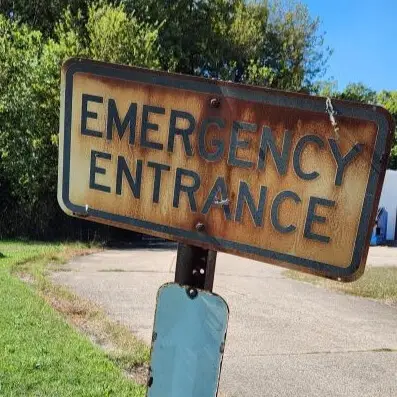Rusted, worn-down emergency entrance sign for a hospital or medical center.