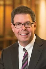 A professional headshot of a man